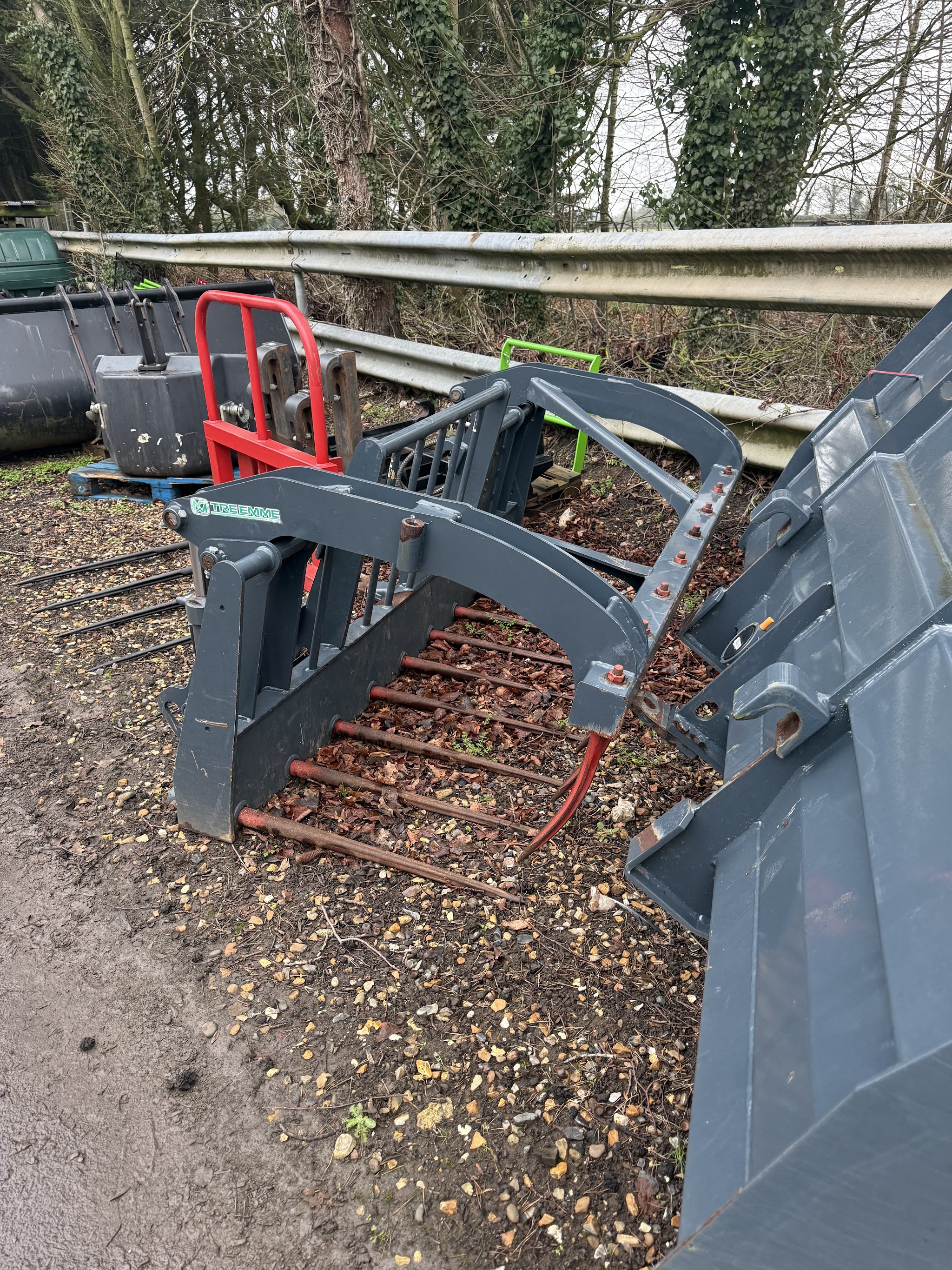 Grey muck grab and bucket attachments on the yard